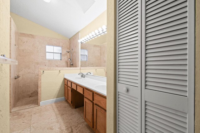 bathroom featuring vaulted ceiling, tiled shower, and vanity