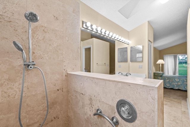 bathroom featuring lofted ceiling, a textured ceiling, and a tile shower