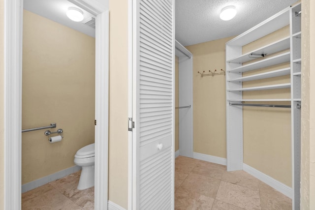 bathroom with toilet, tile patterned flooring, and a textured ceiling