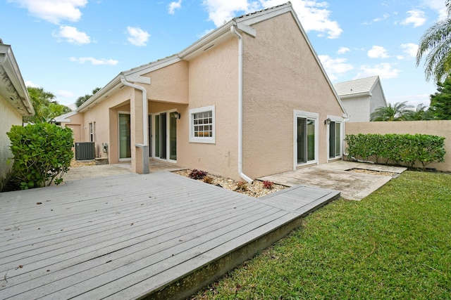 rear view of property featuring central AC unit, a deck, and a lawn