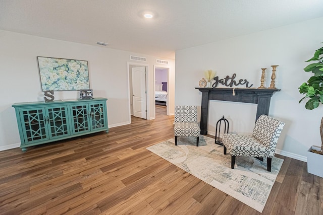 sitting room with hardwood / wood-style flooring and a tiled fireplace