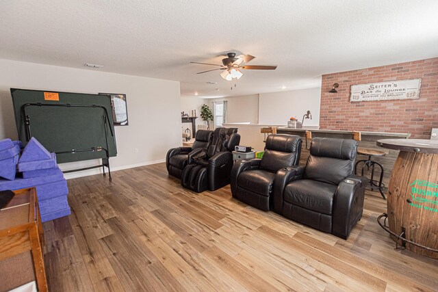 cinema room featuring a textured ceiling, ceiling fan, and light hardwood / wood-style flooring