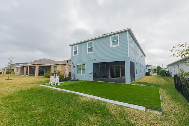 rear view of property featuring a sunroom and a lawn