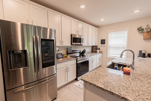 kitchen featuring white cabinetry, sink, light tile patterned floors, light stone counters, and stainless steel appliances