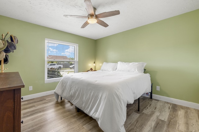 bedroom featuring ceiling fan, a textured ceiling, and light wood-type flooring