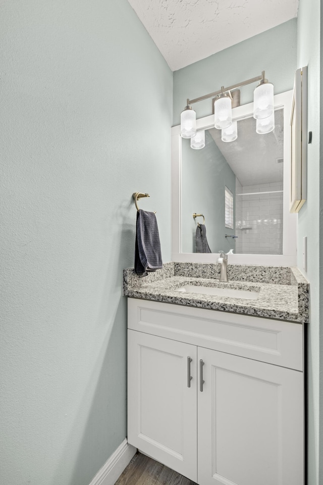 bathroom featuring hardwood / wood-style flooring, vanity, and a textured ceiling