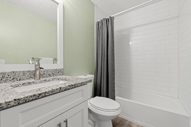 full bathroom featuring hardwood / wood-style floors, shower / tub combo with curtain, vanity, toilet, and a textured ceiling