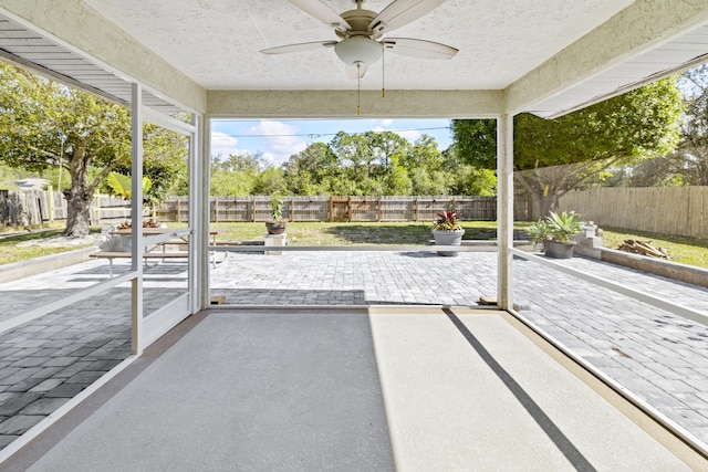 unfurnished sunroom with ceiling fan