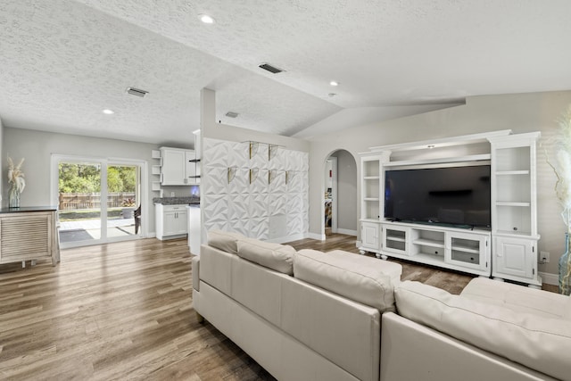 living room with wood-type flooring, vaulted ceiling, and a textured ceiling