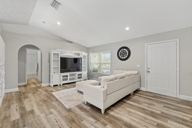 living room featuring vaulted ceiling, a textured ceiling, and light hardwood / wood-style flooring