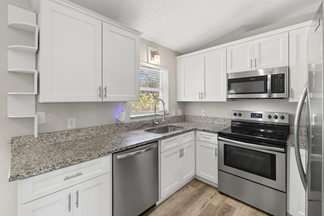 kitchen with stone countertops, appliances with stainless steel finishes, sink, and white cabinets