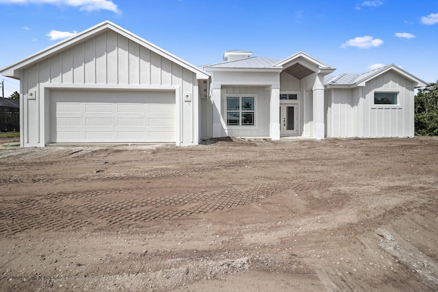 modern farmhouse featuring an attached garage, metal roof, and board and batten siding