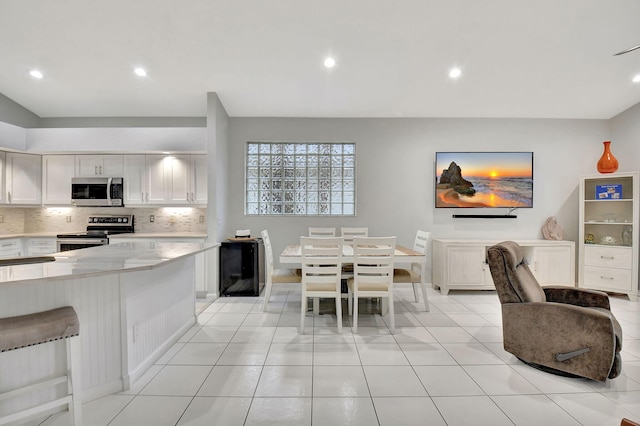 kitchen with light tile patterned flooring, stainless steel appliances, light countertops, white cabinets, and backsplash