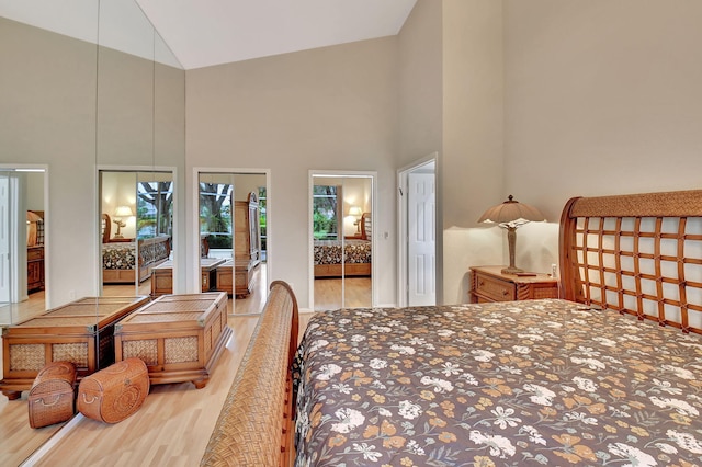 bedroom with a closet, high vaulted ceiling, and light hardwood / wood-style flooring