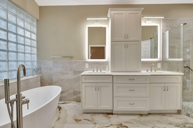 bathroom with a soaking tub, marble finish floor, and a sink