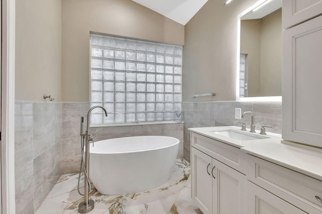 bathroom with vanity, vaulted ceiling, tile walls, and a washtub