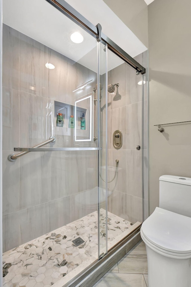 bathroom with a shower with door and toilet