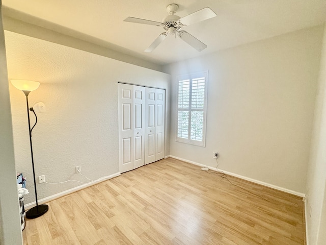 unfurnished bedroom featuring a closet, ceiling fan, baseboards, and wood finished floors