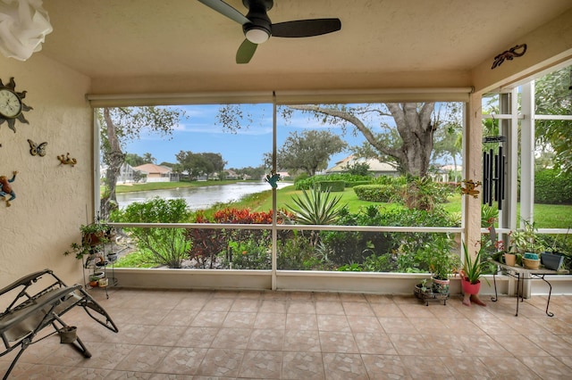 unfurnished sunroom featuring ceiling fan and a water view