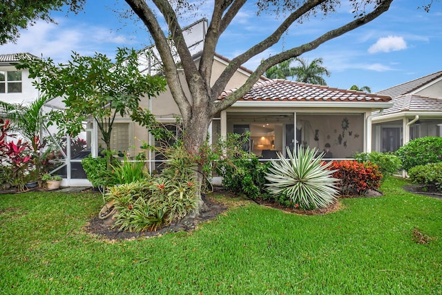 view of front of house featuring a sunroom, glass enclosure, and a front lawn