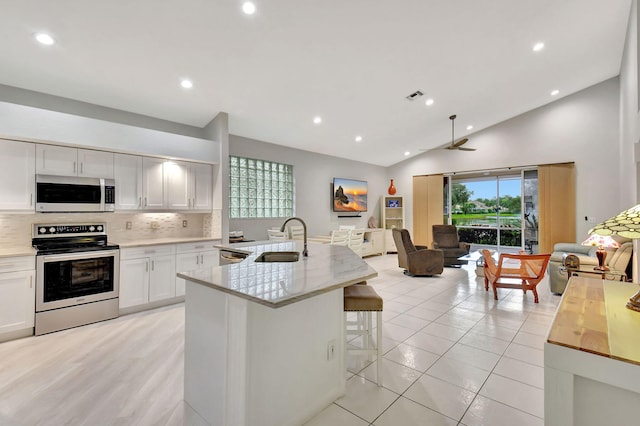 kitchen featuring visible vents, a breakfast bar, a sink, appliances with stainless steel finishes, and open floor plan