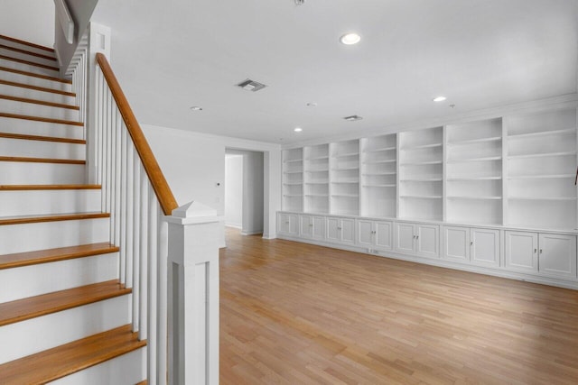 interior space with ornamental molding, built in features, and light hardwood / wood-style floors