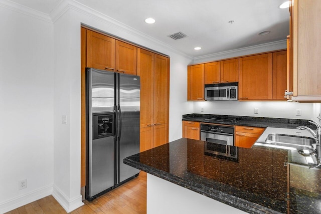 kitchen with ornamental molding, stainless steel appliances, kitchen peninsula, and dark stone countertops