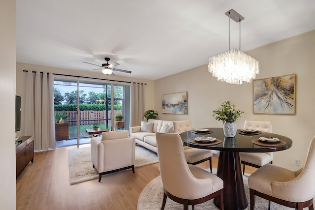 dining room with ceiling fan with notable chandelier and light hardwood / wood-style flooring