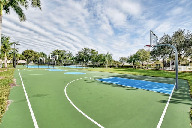 view of sport court featuring tennis court and a lawn