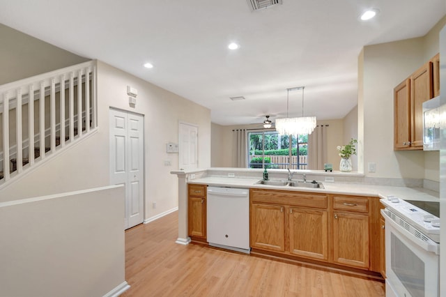 kitchen featuring pendant lighting, white appliances, sink, kitchen peninsula, and light hardwood / wood-style flooring