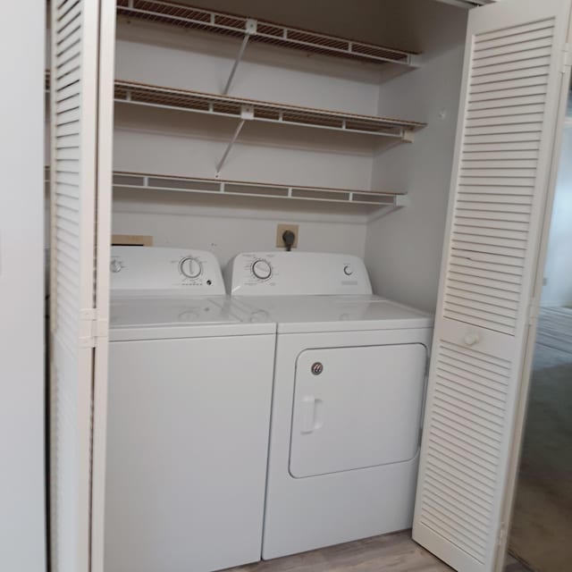 washroom with washer and clothes dryer and light wood-type flooring