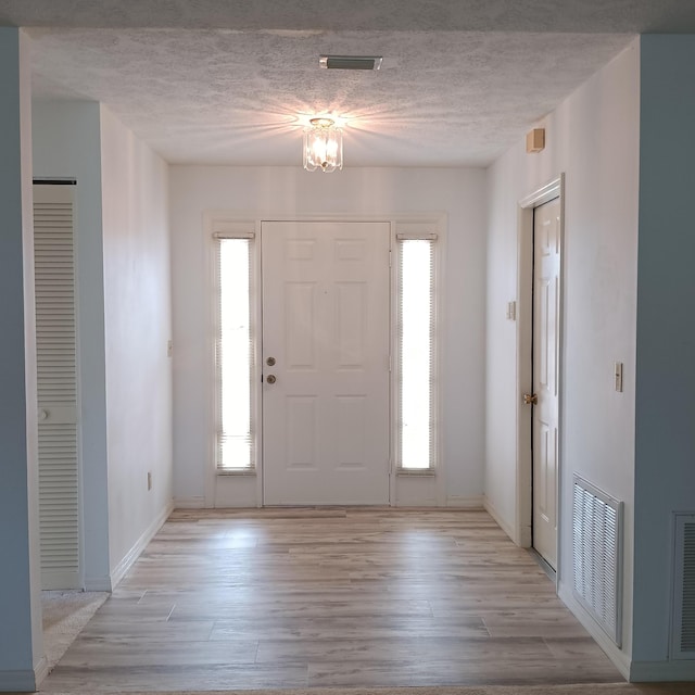 foyer entrance featuring light hardwood / wood-style flooring and a textured ceiling