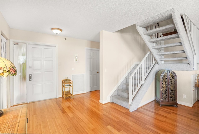 foyer entrance featuring hardwood / wood-style floors and a textured ceiling