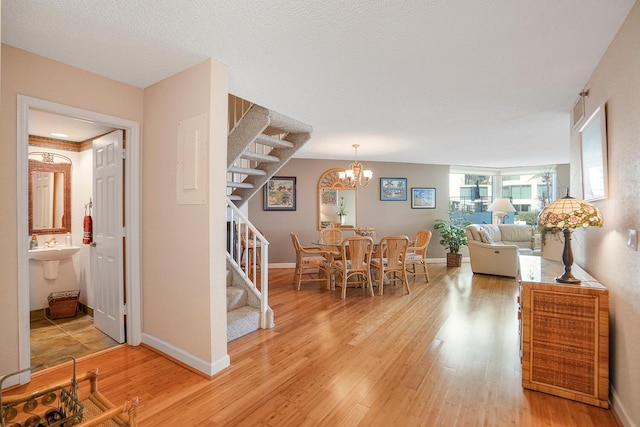 dining area featuring hardwood / wood-style flooring, a textured ceiling, and a notable chandelier