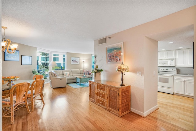 living room with an inviting chandelier, light hardwood / wood-style flooring, and a textured ceiling