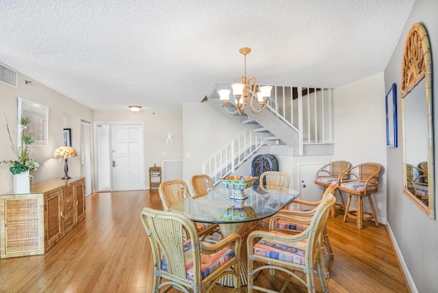 dining space with an inviting chandelier, light hardwood / wood-style flooring, and a textured ceiling