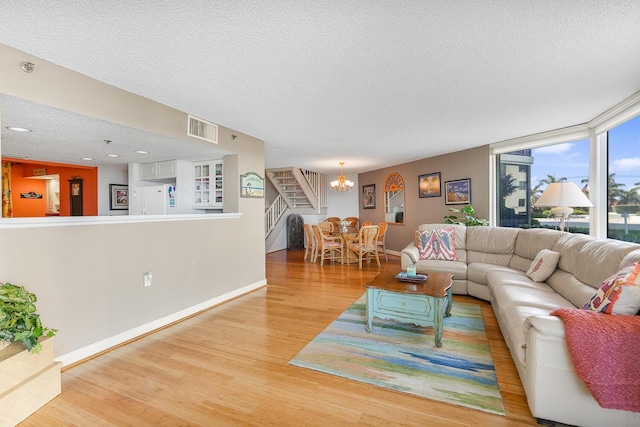 living room featuring a chandelier, a textured ceiling, and light hardwood / wood-style floors