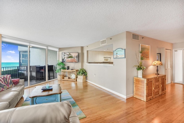 living room with a water view, a textured ceiling, and light hardwood / wood-style floors