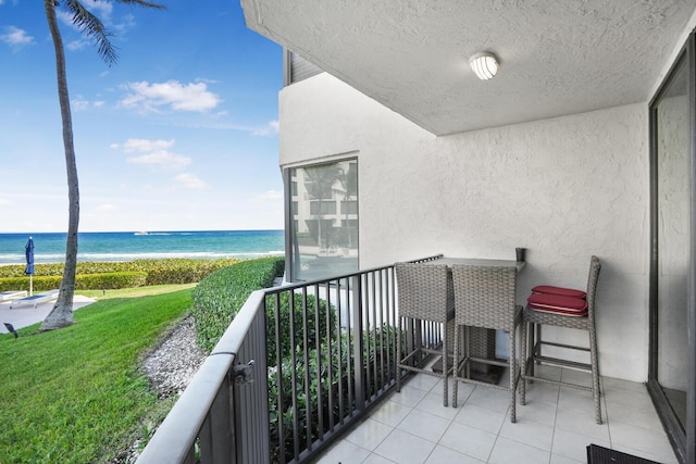 balcony featuring a view of the beach and a water view