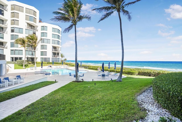 view of swimming pool featuring a yard, a beach view, and a water view