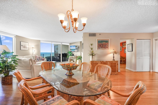 dining area featuring a chandelier, light hardwood / wood-style floors, expansive windows, and a healthy amount of sunlight