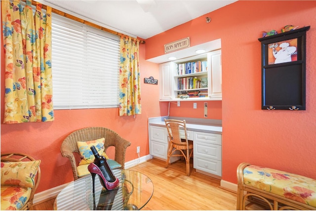 home office with built in desk and light wood-type flooring