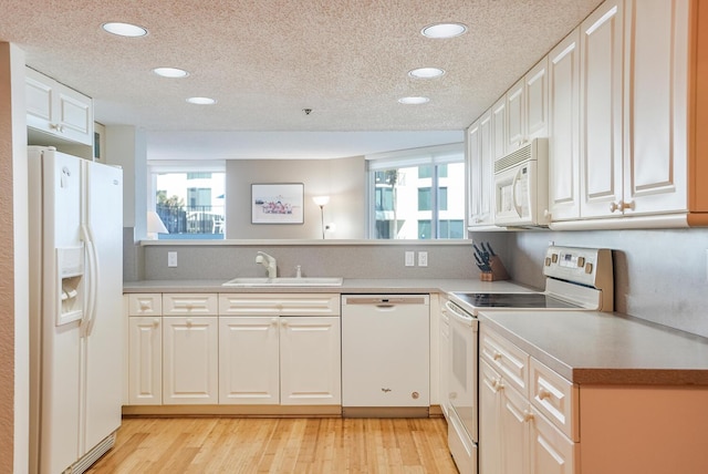 kitchen featuring sink, white cabinetry, a textured ceiling, white appliances, and light hardwood / wood-style floors