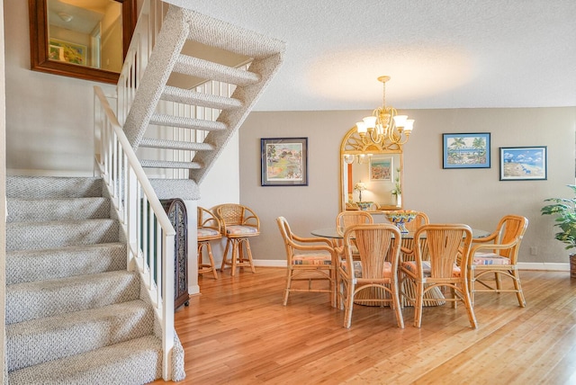 dining area with a notable chandelier, hardwood / wood-style flooring, and a textured ceiling