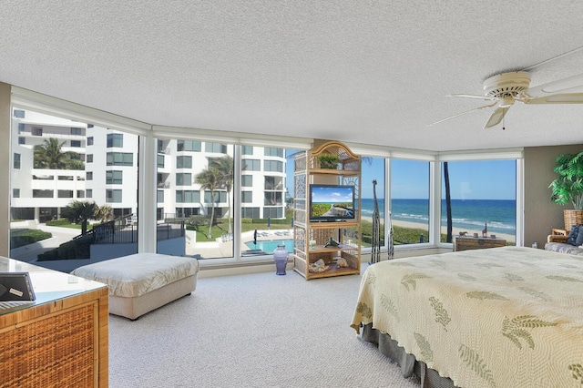 bedroom featuring ceiling fan, carpet floors, floor to ceiling windows, and a textured ceiling