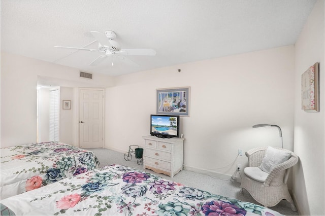 carpeted bedroom featuring ceiling fan and a textured ceiling