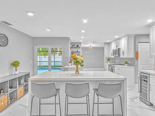 kitchen with wine cooler, white cabinets, tasteful backsplash, and stainless steel appliances