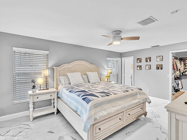 bedroom with a spacious closet, a closet, multiple windows, and ceiling fan