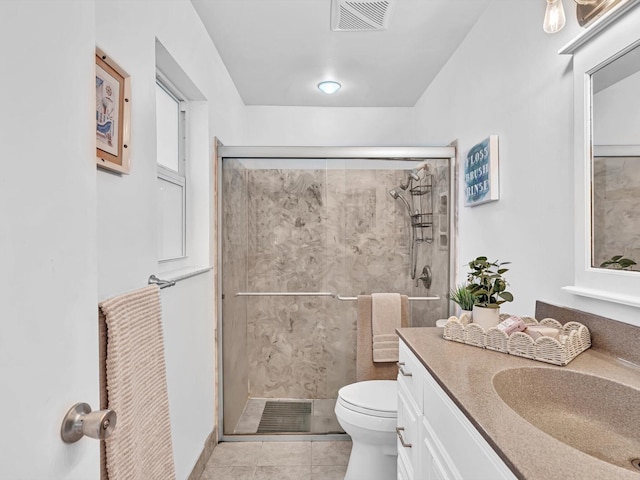 bathroom featuring walk in shower, vanity, tile patterned flooring, and toilet