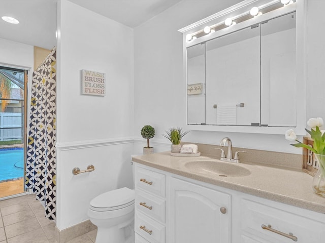 bathroom with toilet, vanity, and tile patterned flooring